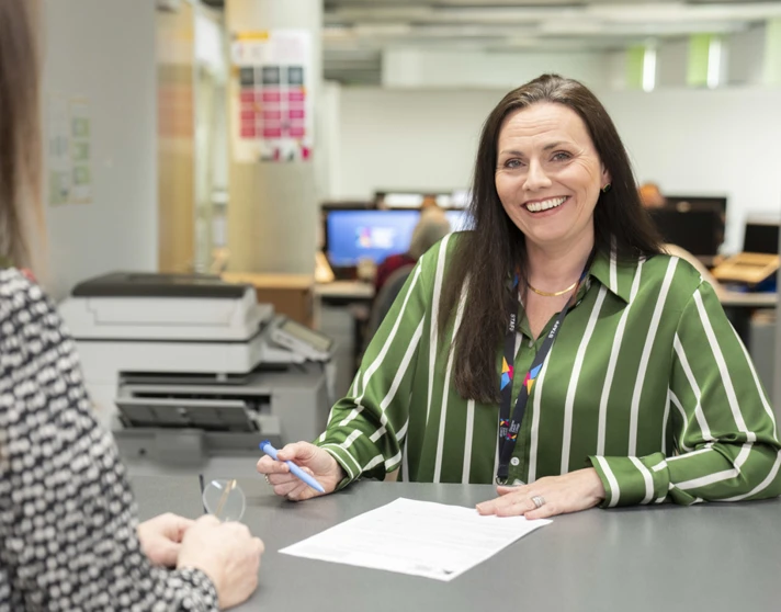 Staff member assisting a student with paperwork at a help desk in Glasgow Kelvin College Staff member assisting a student with paperwork at a help desk in Glasgow Kelvin College